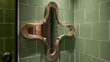 Espejo con un marco decorativo sobre una pared con azulejos verdes.