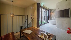 A modern living room with a wooden coffee table, a leather sofa, and a staircase leading to a balcony. - Hotel March (Daejeon)
