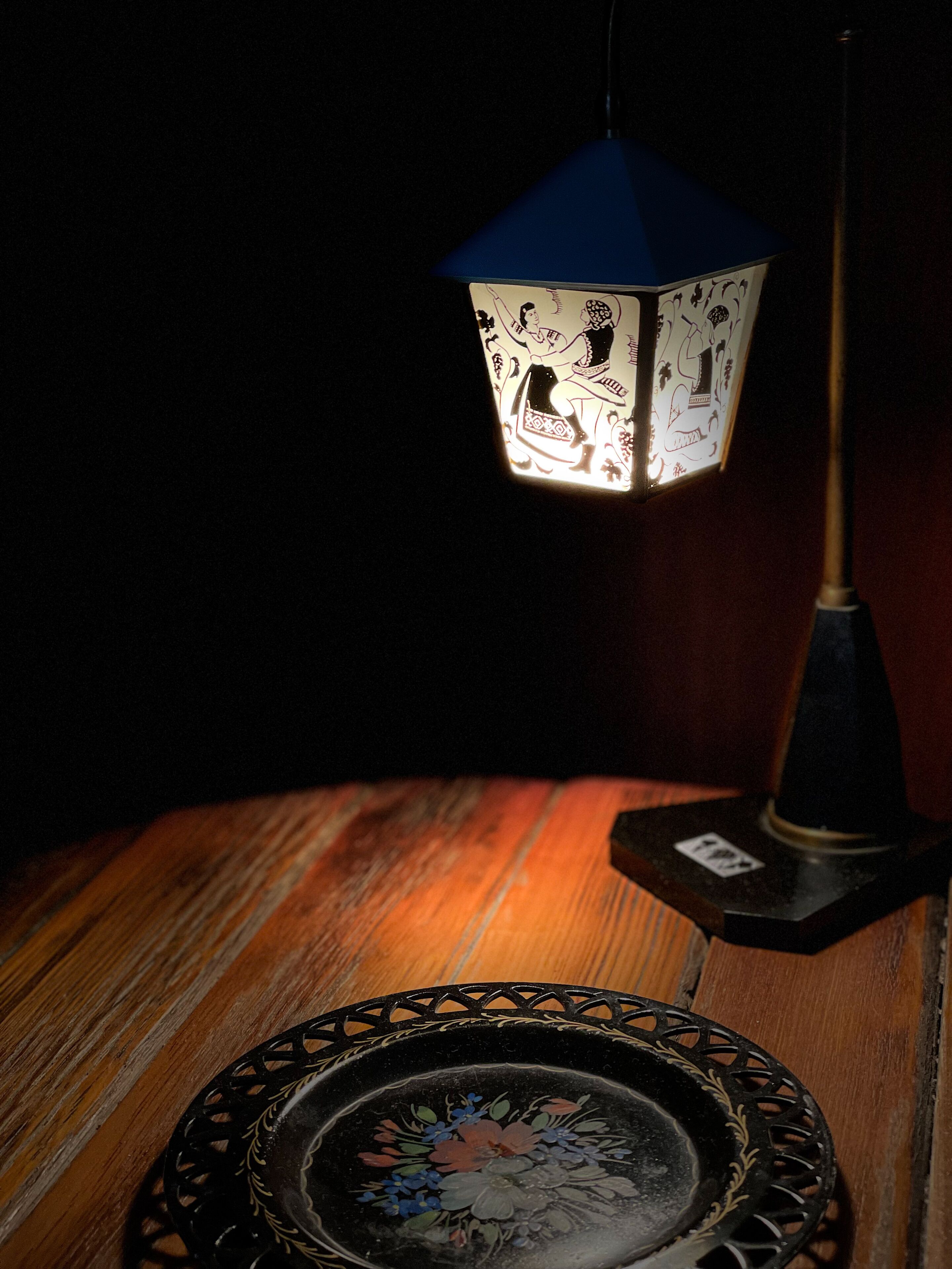 Ein Tisch mit einer verzierten Platte und einem Laternenlicht mit einem gemusterten Schirm.