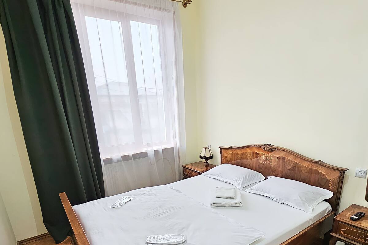 A neatly made bed with white linens, a wooden headboard, and a green chair.