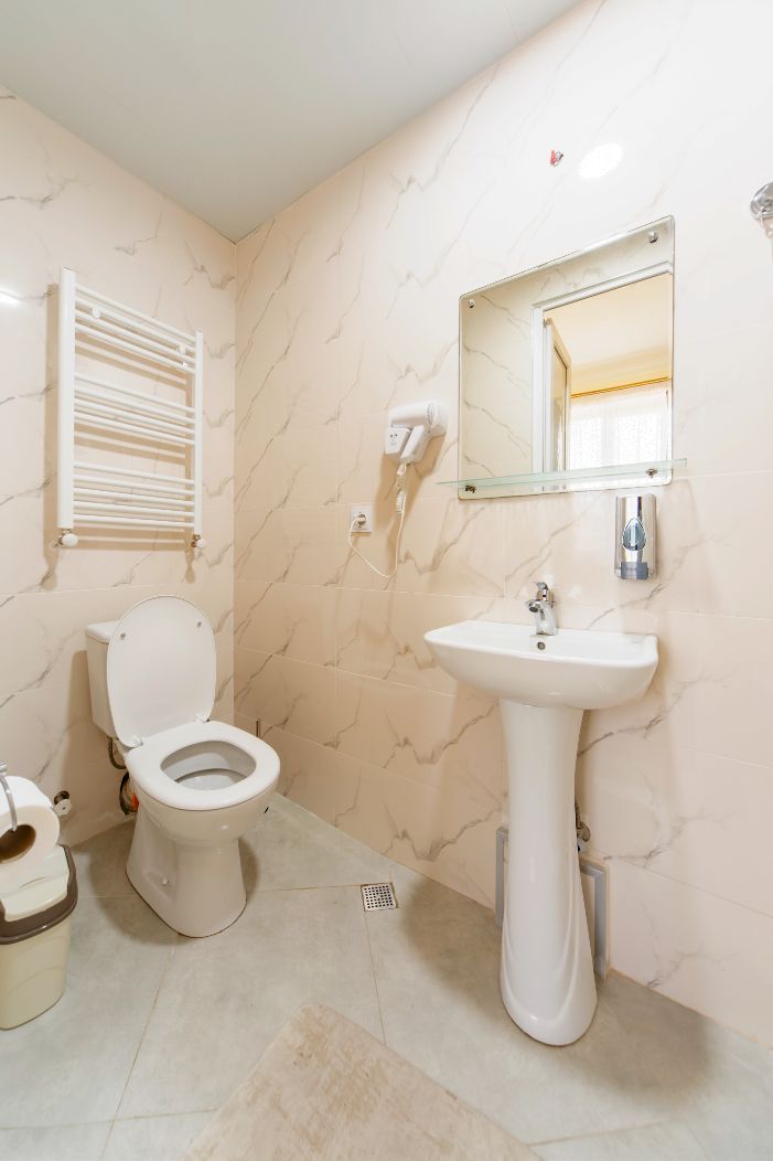 A bathroom with a toilet, sink, and a towel rack.