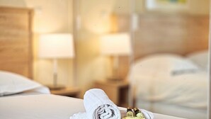 A neatly made bed with a rolled white towel and two bottles of lotion on the bed. - Studio Commandant André 22 by Viva Riviera (Cannes)