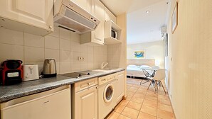 A compact kitchen with a washing machine, a coffee maker, and a toaster. - Studio Commandant André 22 by Viva Riviera (Cannes)