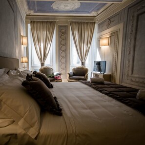 A large bed with a headboard, two armchairs, a small table with a lamp, and a television on a stand. - San Pier Novello in Oltrarno (Florence)
