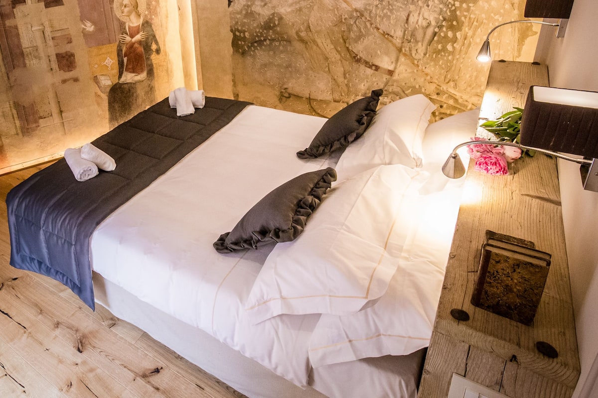 A hotel room with a large bed, a mural on the wall, and a wooden floor.