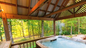 A hot tub in a wooden deck with a view of a forest.
