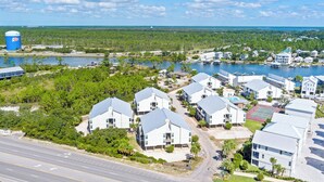 A residential area with modern houses, a tennis court, and a body of water.