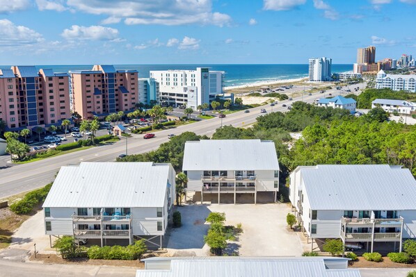 A coastal hotel with multiple buildings, a beach view, and a road leading to the beach.