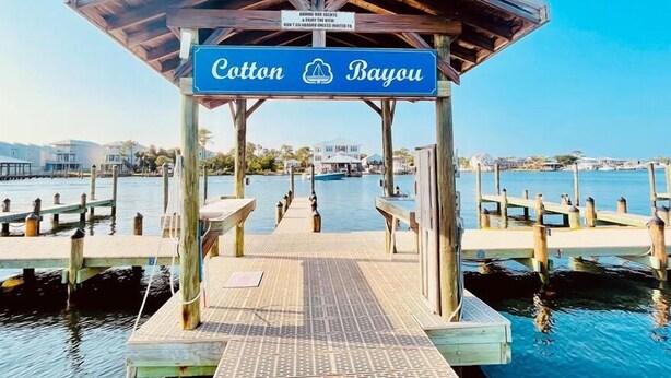 A wooden pier leading to a covered area with a sign reading "Cotton Bayou."