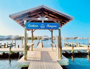 A wooden pier leading to a covered area with a sign reading "Cotton Bayou."