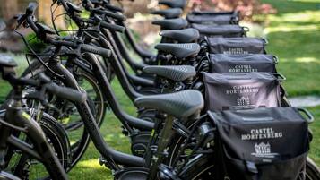 Een rij fietsen met bevestigde opbergtassen, voorzien van de tekst 'Castel Hortenberg'.
