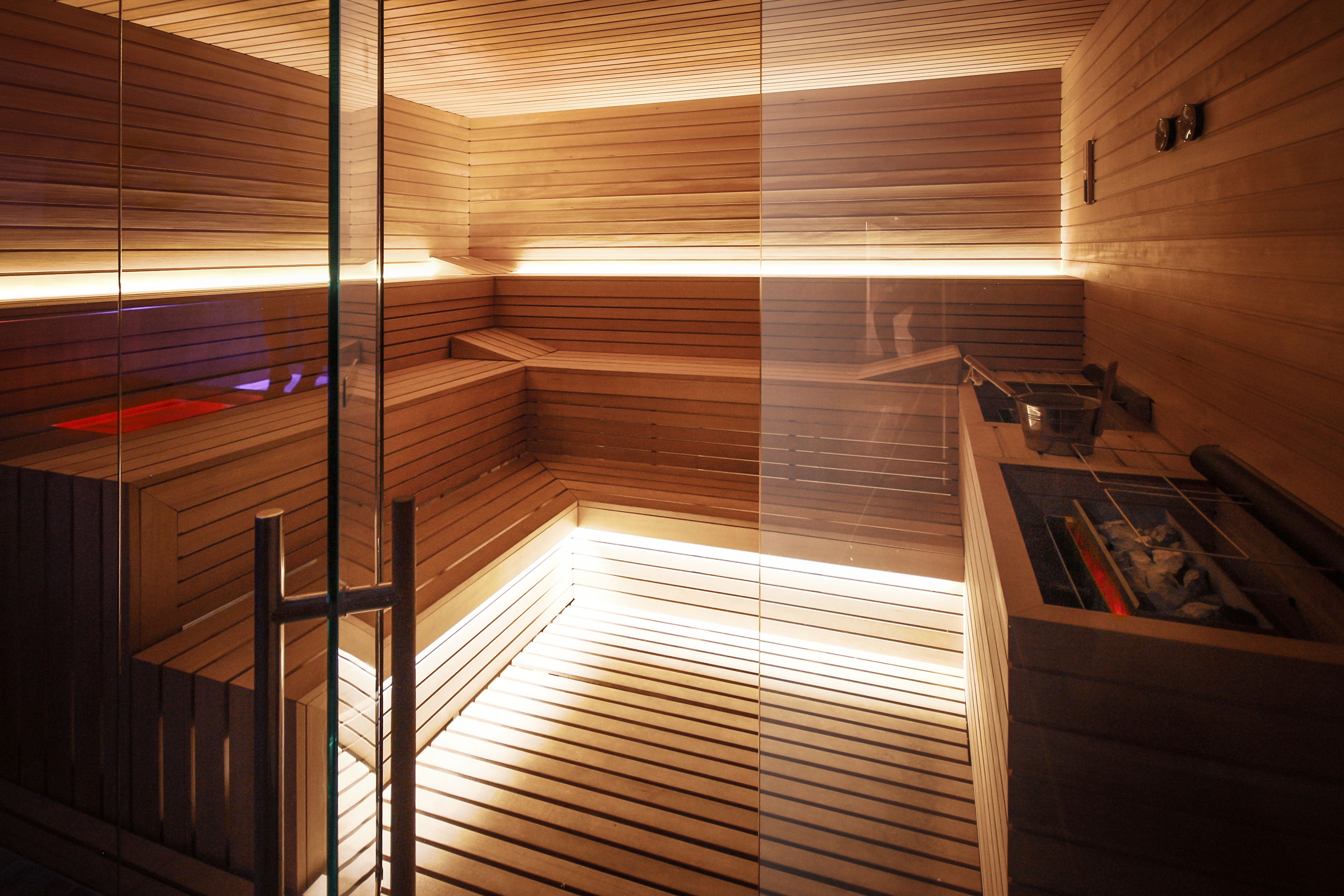 Uma sauna com ripas de madeira, divisória de vidro e sala de vapor.
