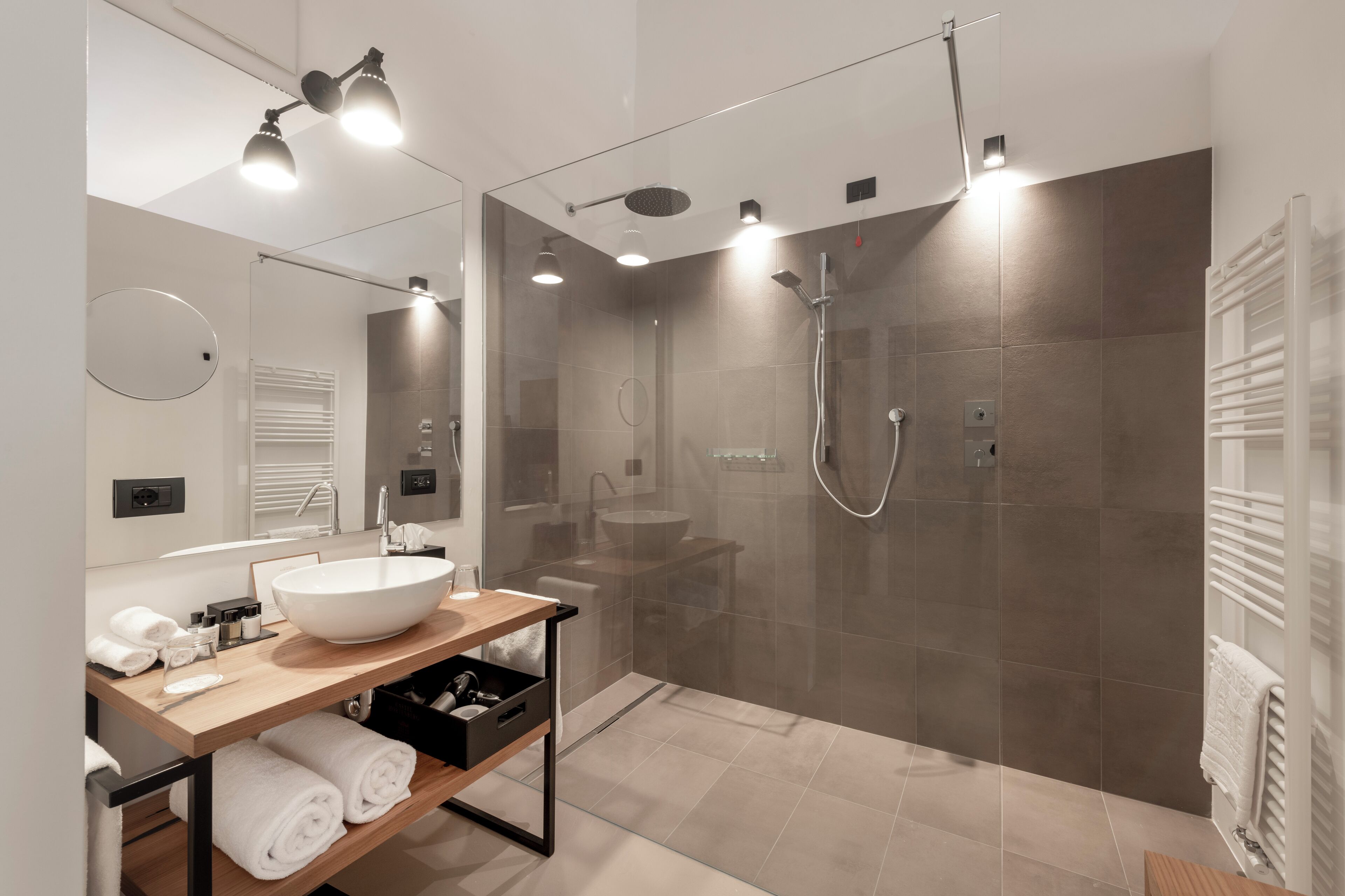 Un baño moderno con un lavamanos grande, espejo y ducha con mampara de vidrio.