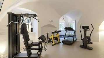 Une salle de sport équipée d’un banc de développé couché, d’un tapis de course et d’un appareil elliptique.