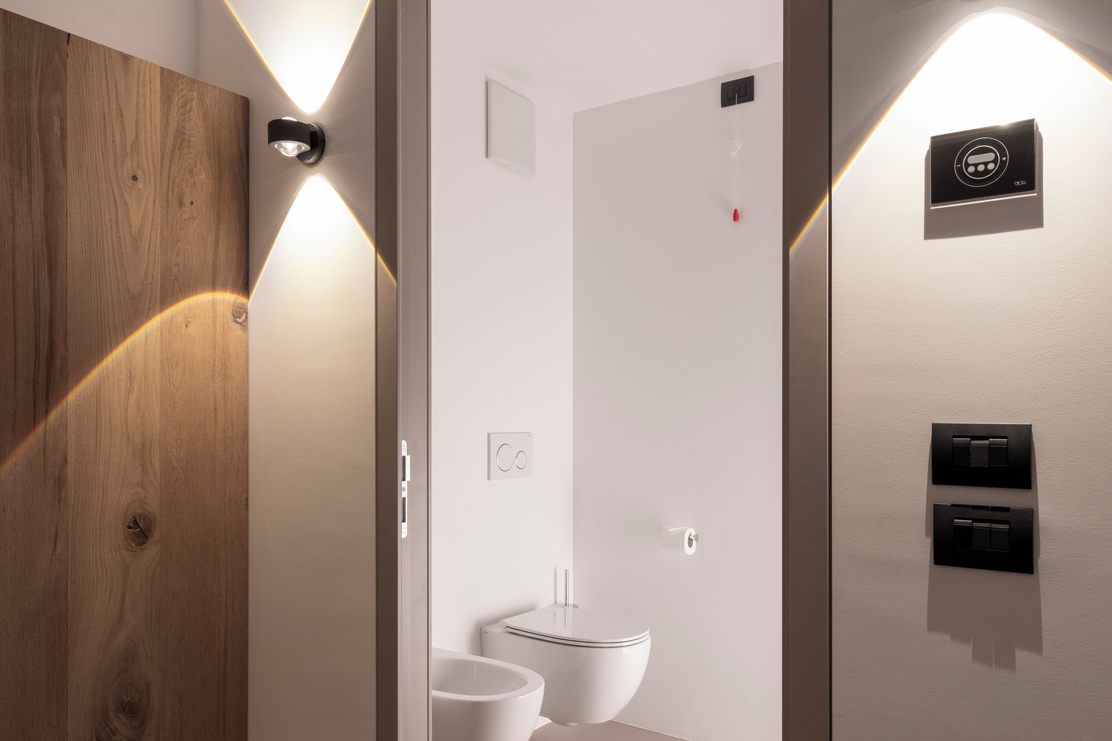 Un baño moderno con tocador de madera, inodoro y zona de ducha.