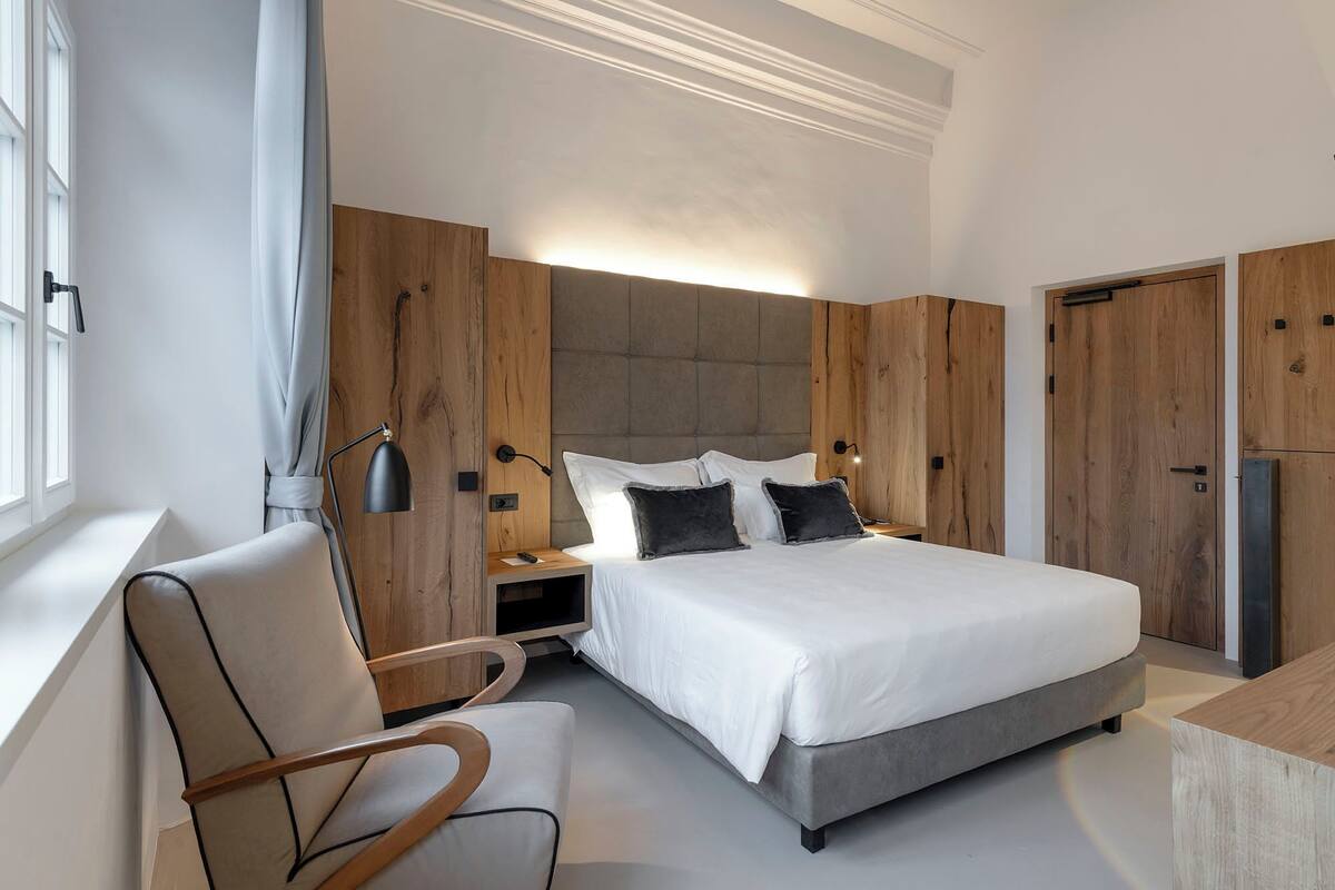 Un dormitorio moderno con una cama grande, paneles de madera, un escritorio y una silla.