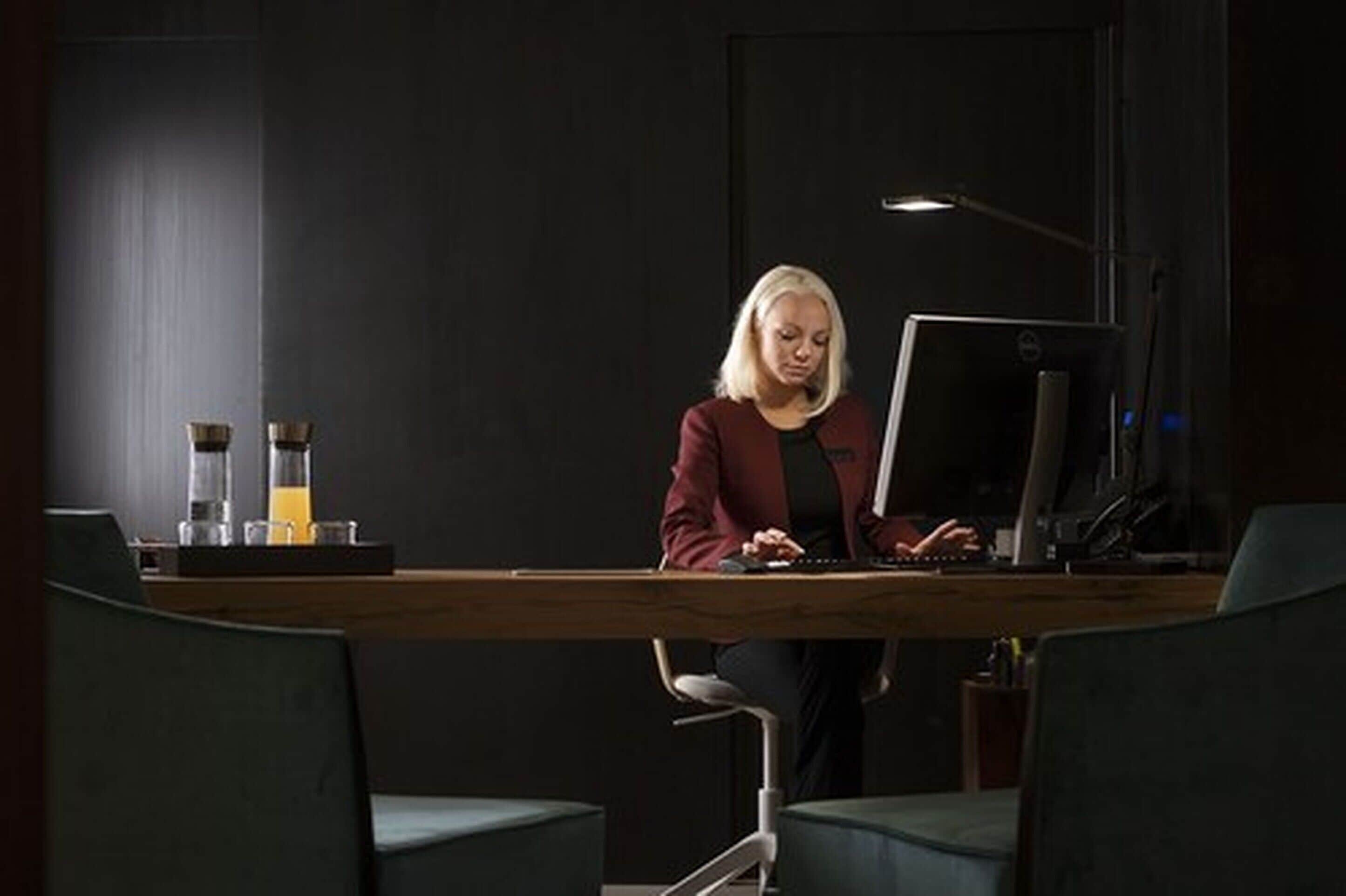 A person working at a desk with a computer, a lamp, and a coffee maker on the table.