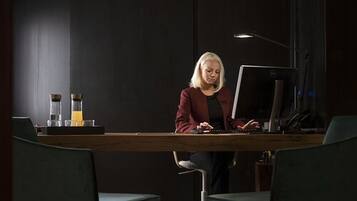 A person working at a desk with a computer, a lamp, and a coffee maker on the table.