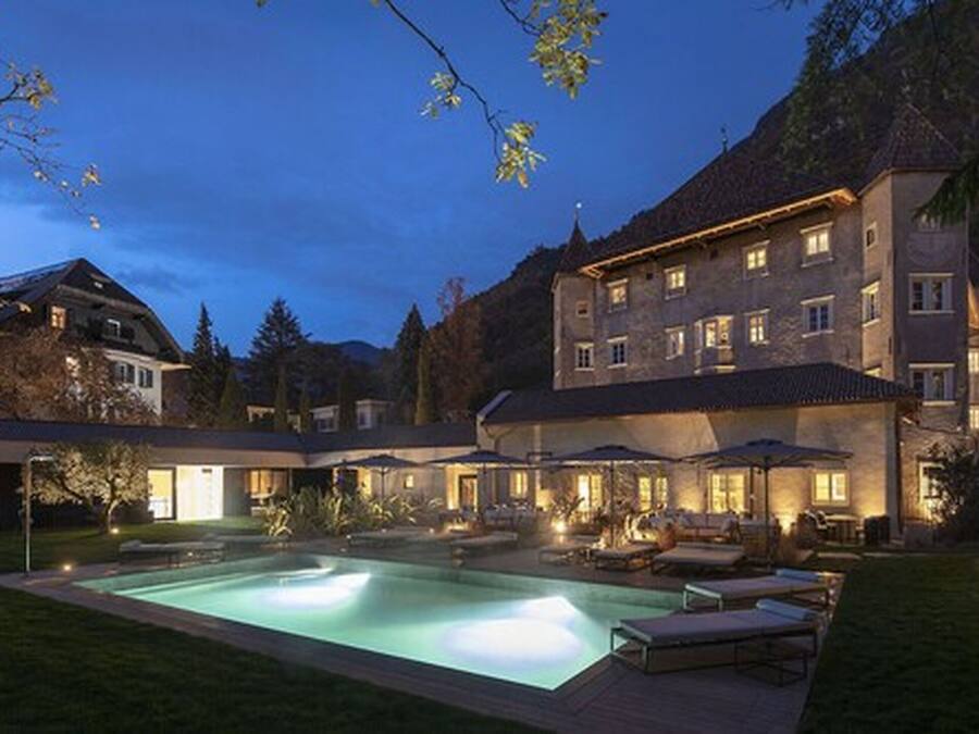 A large building with a swimming pool and outdoor seating area at dusk.