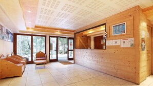 Zona de recepción con paneles de madera, mostrador de recepción y área de estar con bancos.
