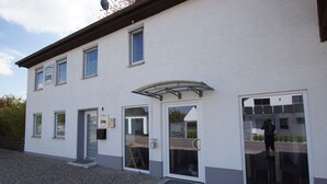 A two-story building with a white exterior, multiple windows, and a covered entrance. - Pension Obstgarten (Achstetten)
