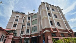 A multi-story hotel with a pink facade, large windows, and a flag on top. - Shwe Pe Ti Hotel (Mandalay)