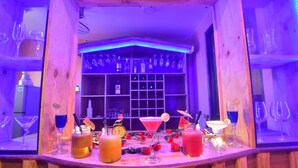 A bar area with wooden shelves displaying various bottles and glasses, a counter with drinks and a decorative mirror. - Shwe Pe Ti Hotel (Mandalay)