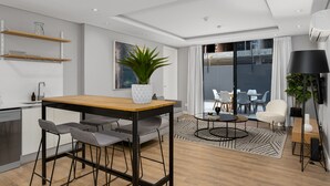 A modern kitchen with a dining area, a large window, and a living space with a sofa and chairs. - Best of Both (Cape Town)