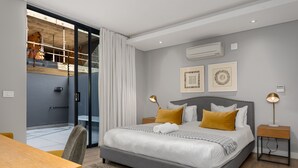 A modern bedroom with a grey bed, yellow pillows, and a wooden nightstand. - Best of Both (Cape Town)