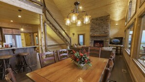 Un interior de madera con una mesa de comedor, sillas, chimenea y una escalera.