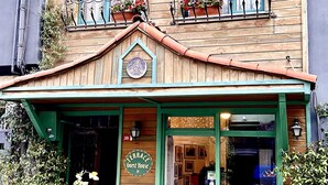 A guesthouse with a wooden facade, green trim, and flower boxes on the windows. - Terrace Guesthouse (Istanbul)