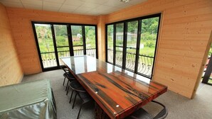A conference room with a large wooden table, chairs, and a view through large windows. - Fu Chuan Garden Homestay (Nanzhuang)
