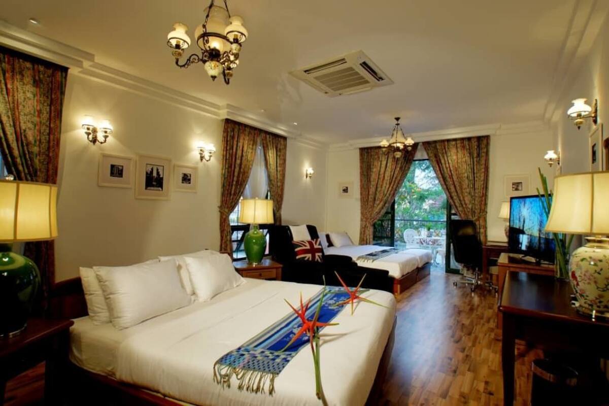 A hotel room with two beds, a television, a desk, and a view of the outdoors.