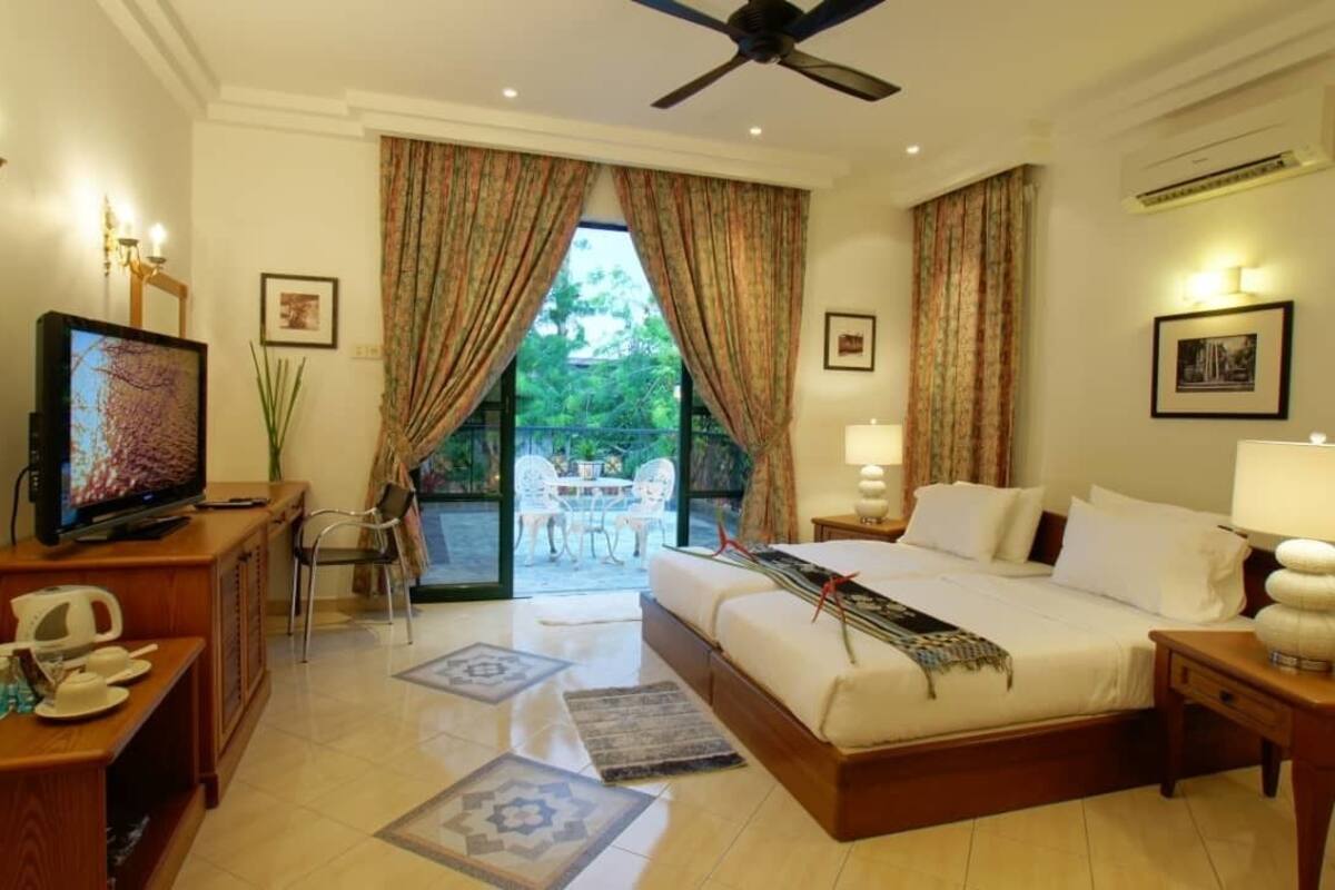 A hotel room with a bed, a desk with a television, a coffee maker, and a view of the outdoors.