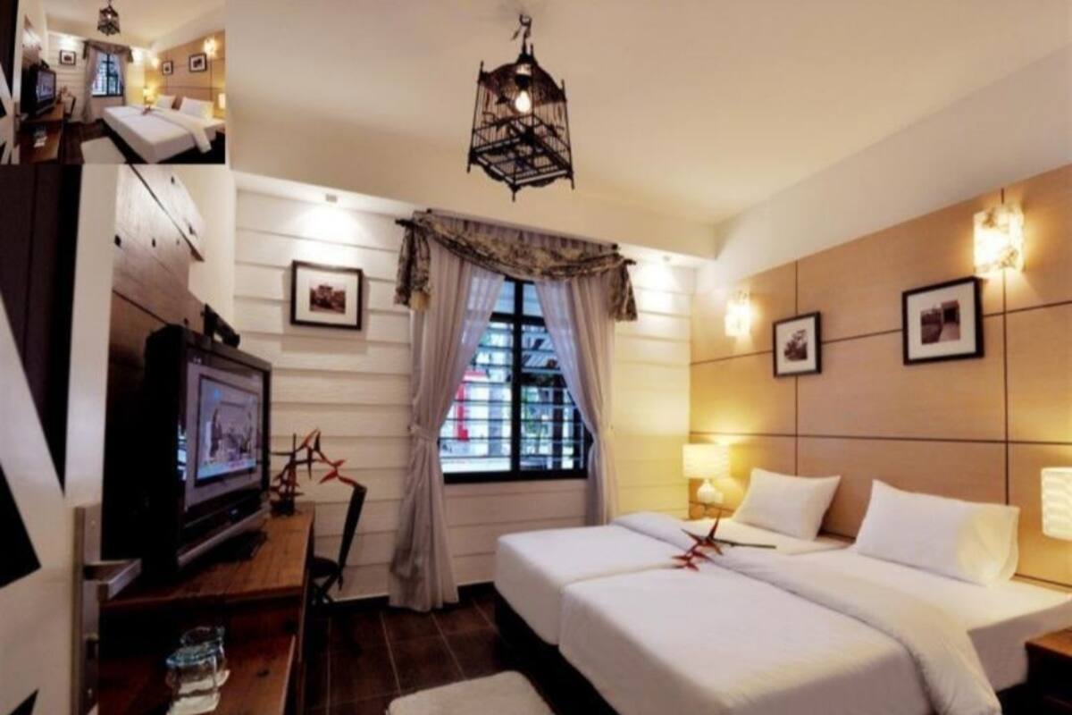 A hotel room with two beds, a television, a desk with a chair, a window with curtains, and wall-mounted picture frames.