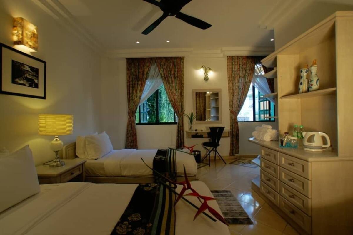 A hotel room with a bed, a desk, a chair, a dresser, and a ceiling fan.