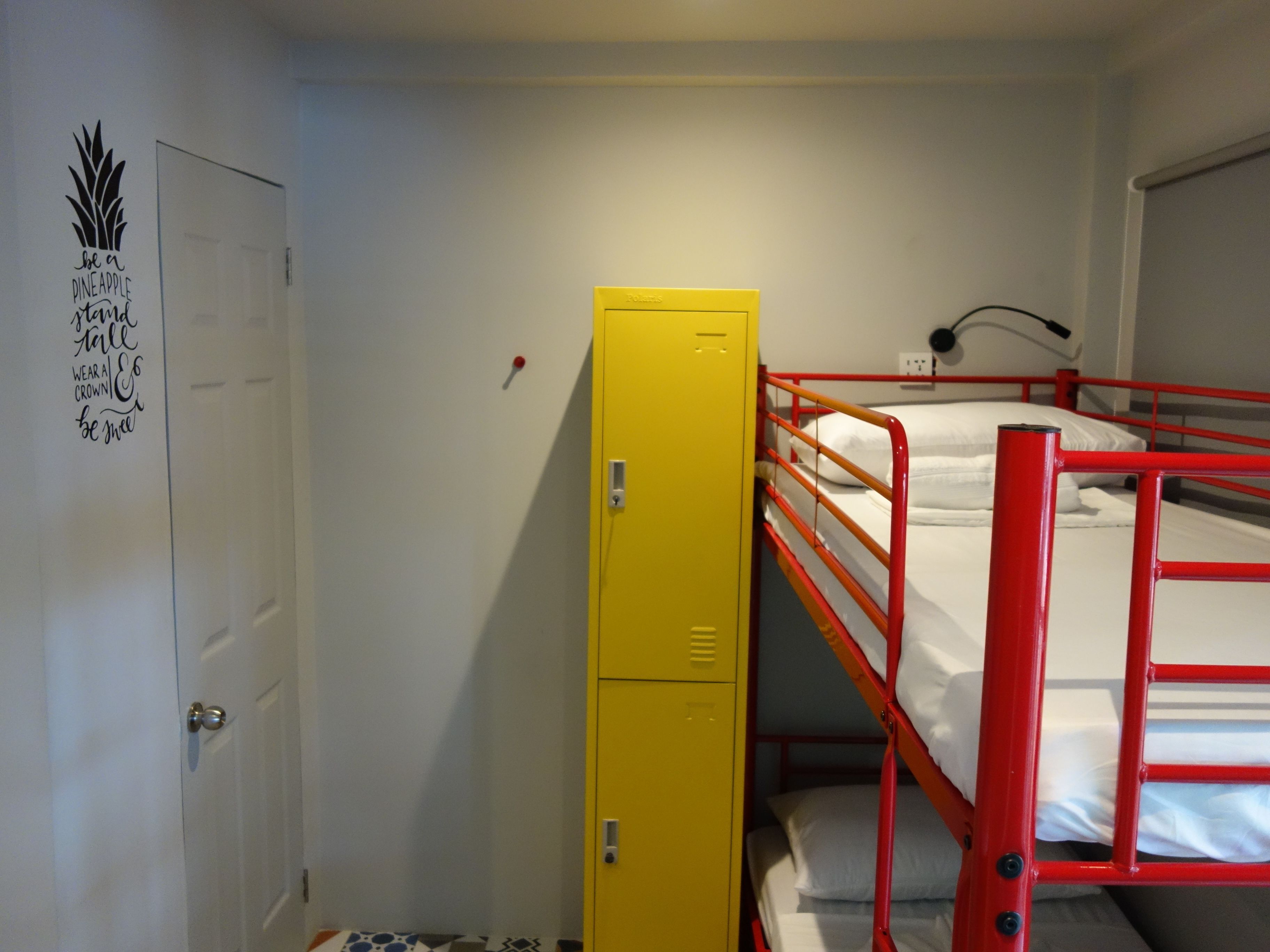 A dormitory room with bunk beds, a yellow storage unit, and a motivational poster on the wall.