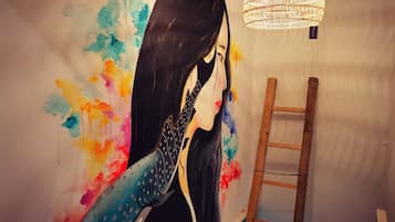 A room with a mural of a woman holding a guitar, a wooden ladder, and a hanging light fixture.