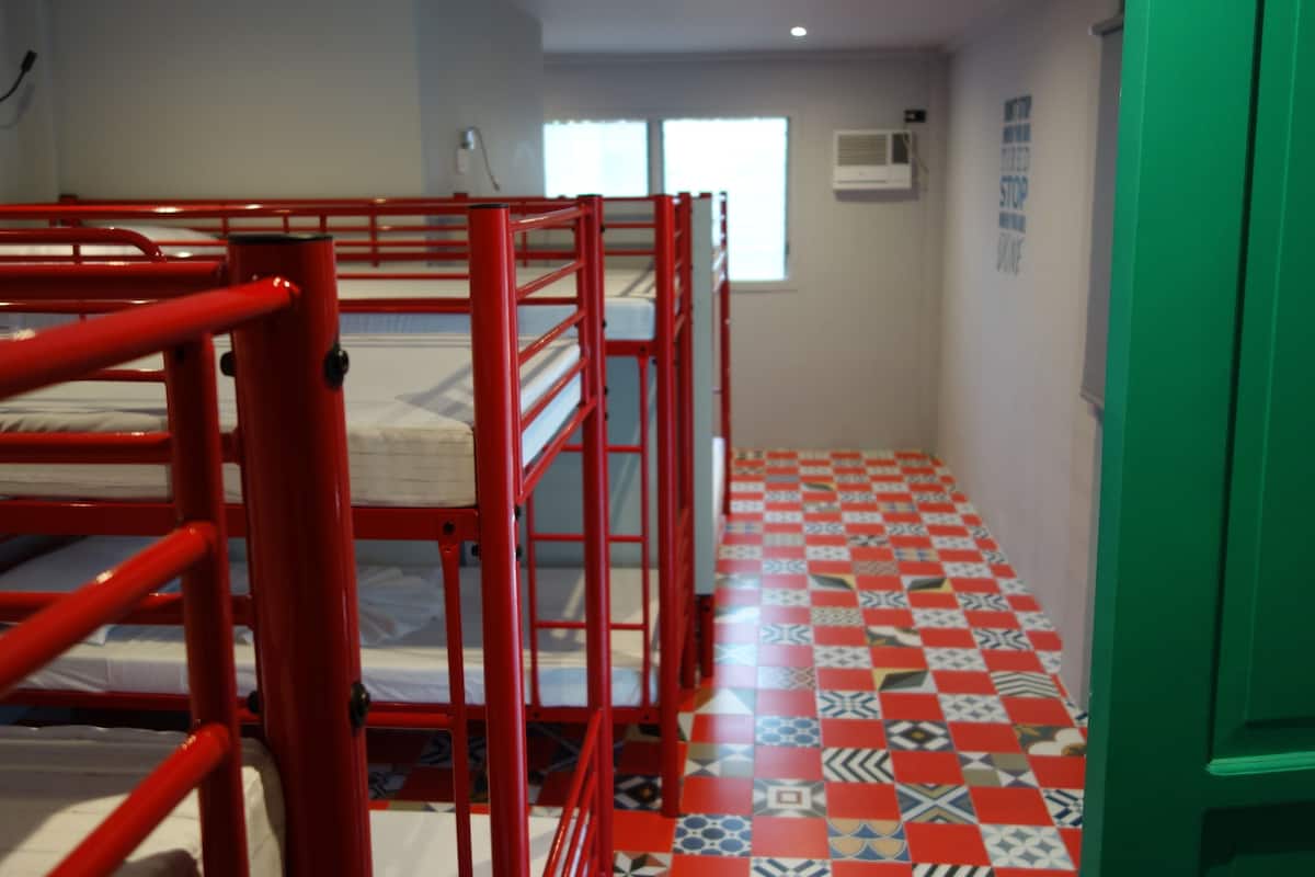 Una habitación con literas, piso estampado y puerta verde.