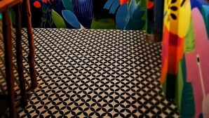 A room with a colorful mural on the wall, a patterned floor, and a wooden chair. - Way Shack Hostel (Oslob)