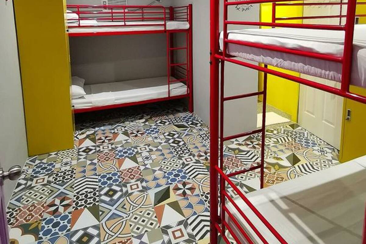 Un dormitorio con literas, baldosas de suelo estampadas y una puerta amarilla.