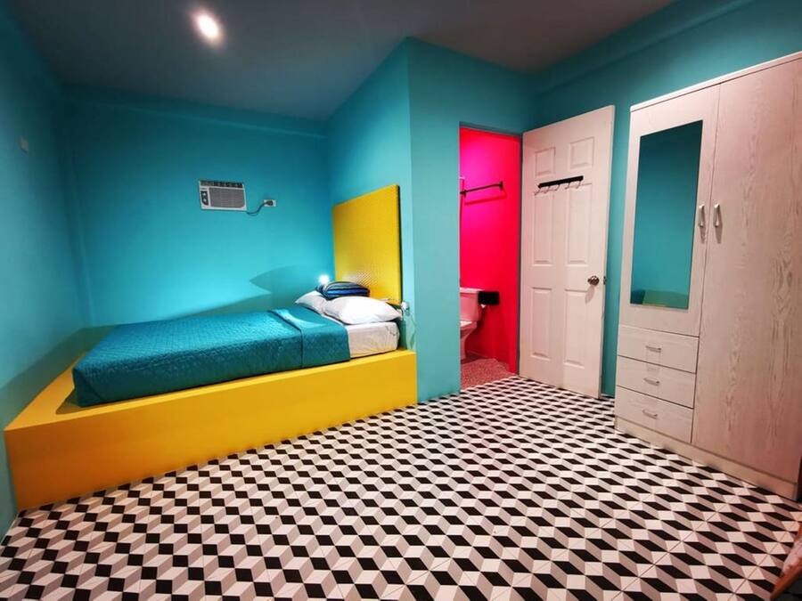 Un dormitorio con cama, armario y baño visible a través de una puerta abierta.