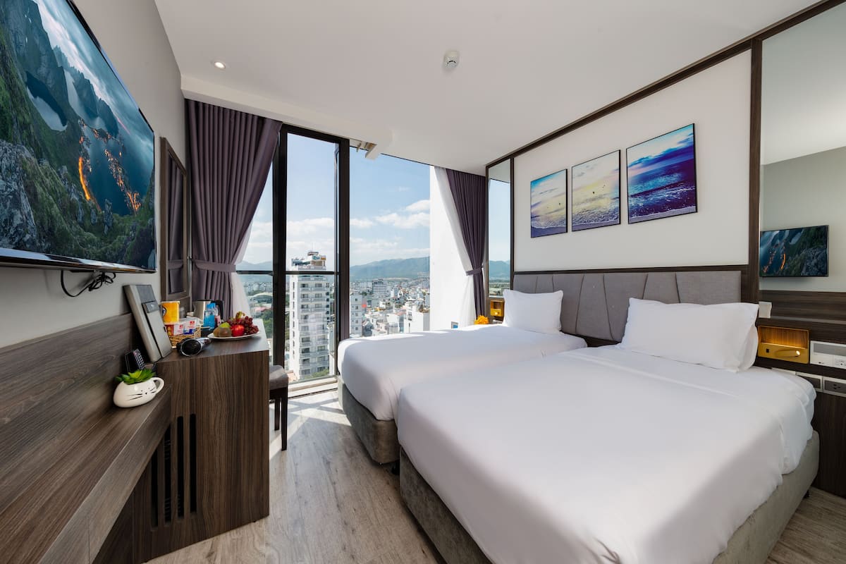 Une chambre d’hôtel moderne avec deux lits, une grande télévision et une vue sur la ville.