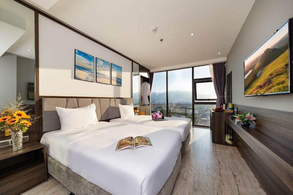 Une chambre d'hôtel moderne avec deux lits, une grande fenêtre et des œuvres d'art accrochées aux murs.