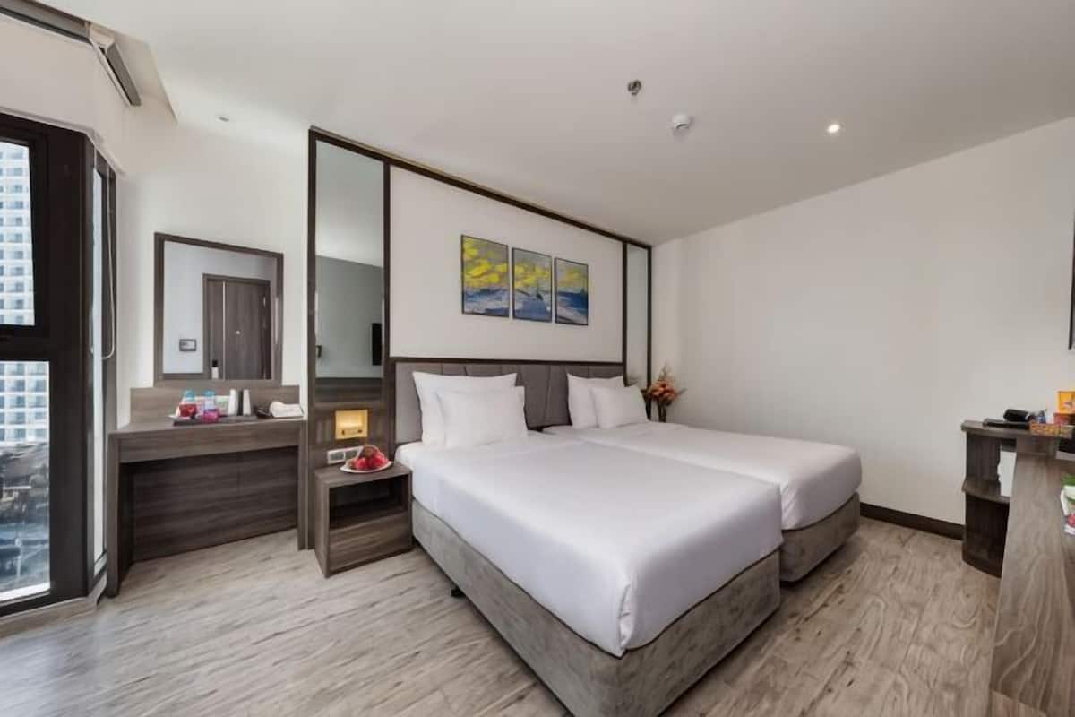 Une chambre d’hôtel avec un grand lit, un bureau avec un miroir, une petite table et une vue sur la ville.