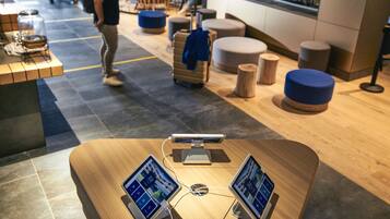 Un moderno vestíbulo de hotel con un mostrador de recepción de madera, dos monitores y un quiosco digital.