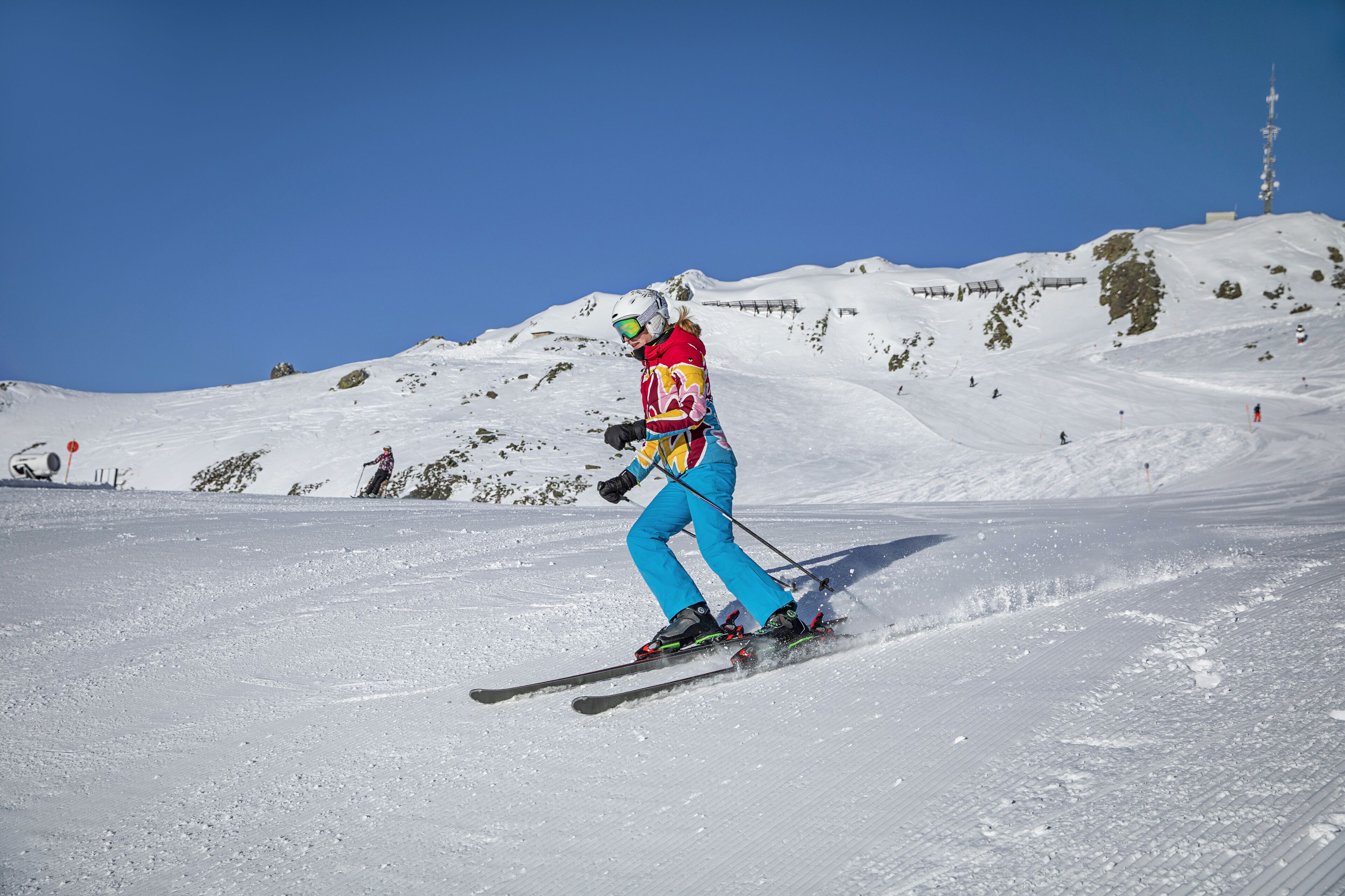 A person skiing on a snowy slope with a clear blue sky.