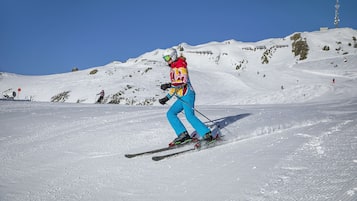A person skiing on a snowy slope with a clear blue sky.
