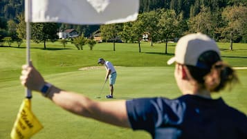 A golf course with a flagstick and a golfer in the foreground.