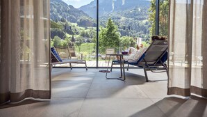 A balcony with two lounge chairs and a table, overlooking a mountainous landscape. - TUI BLUE Montafon (Tschagguns)